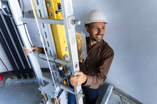 Smiling engineer descends basement stairs in a wind turbine base