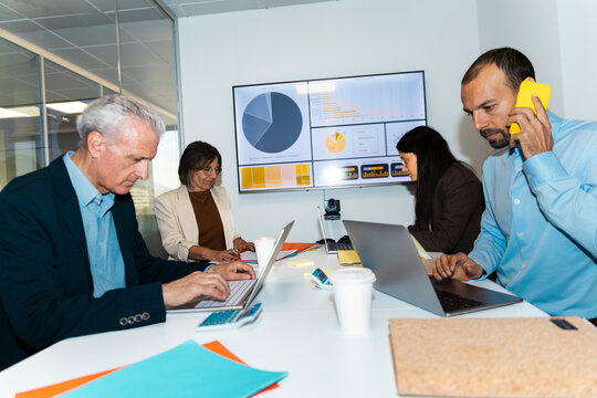 A businessman and a businesswoman work on laptops in the office