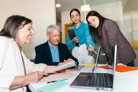 Colleagues review a presentation on a laptop in the office