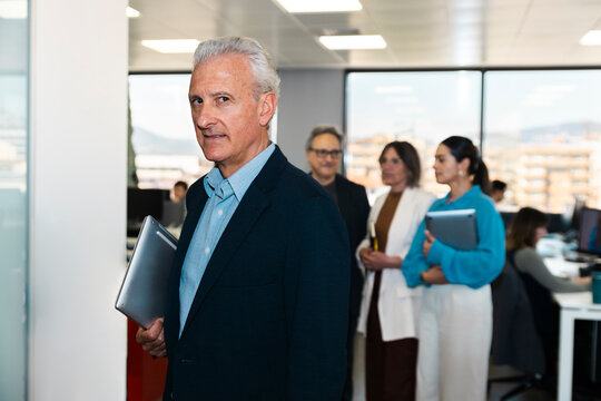 Confident businessman holds a laptop in the office