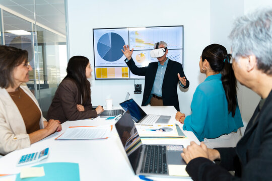 Businessman wearing VR headset gives presentation in office