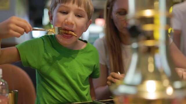 Young boy enjoying a meal at a korean barbecue restaurant