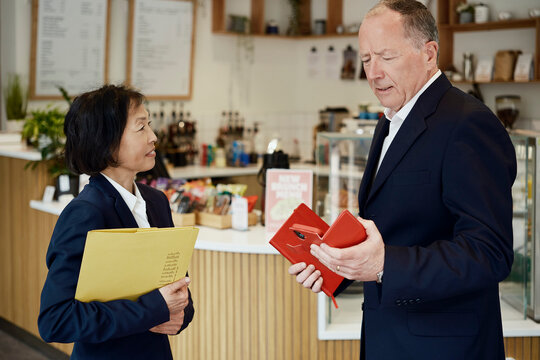 Businessman and businesswoman discuss reports in a coffee shop