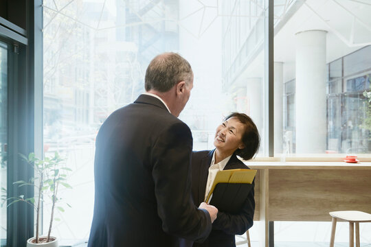 A businessman and a businesswoman chat in a coffee shop