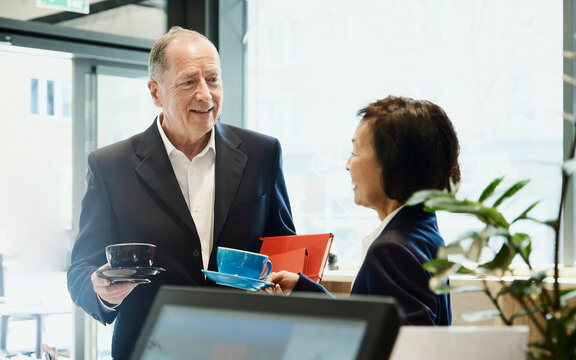 A businessman and businesswoman drink coffee in a cafe