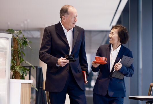 Businessman and businesswoman walk and talk in a coffee shop