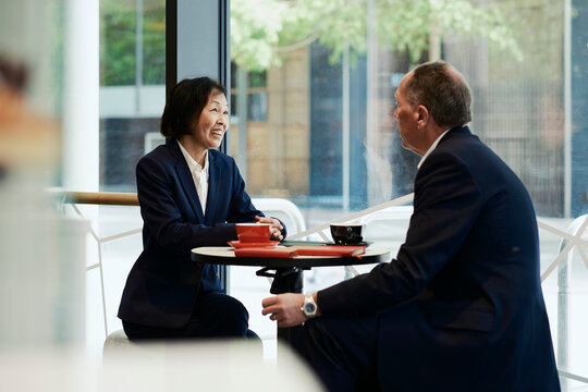 Businessman and businesswoman chat at a coffee shop