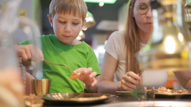 Mother teaching her son how to use cutlery