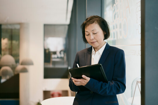 A businesswoman works on a tablet computer in a coffee shop