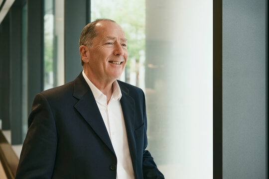 Smiling businessman looking out window in an office building