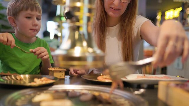 Mother and son enjoying korean barbecue restaurant dinner