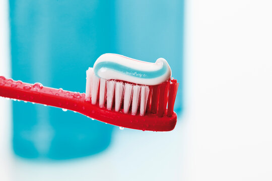 Close up of toothbrush and toothpaste with mouthwash bottle in background
