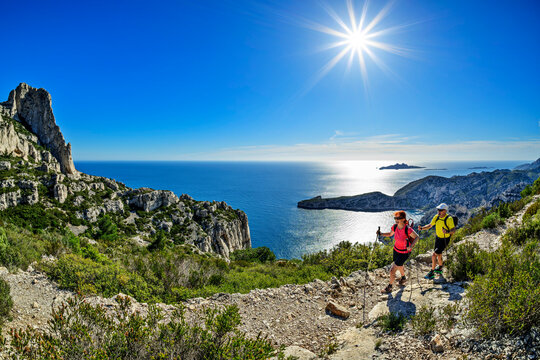Man and woman hike a rocky trail near the sea in France