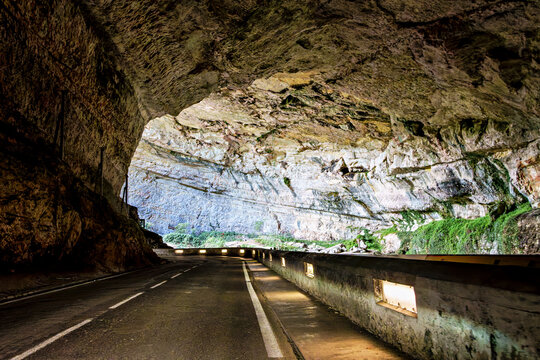 The Mas d'Azil Cave in France features a grand entrance surrounded by lush greenery.