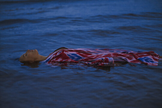 A woman floats in the sea wearing a traditional patchwork robe