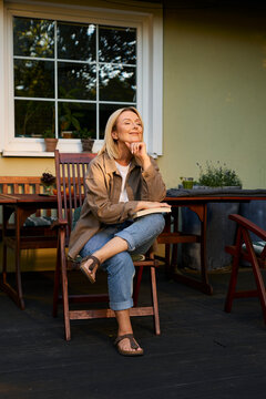 Happy woman sitting outdoors with a book on patio in backyard