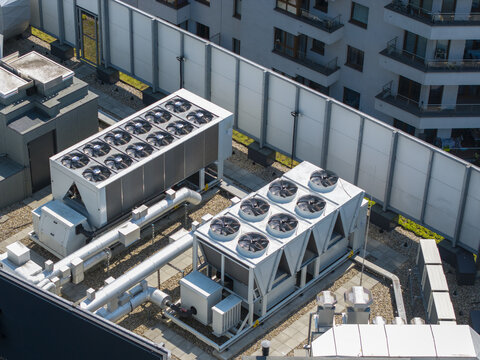 Aerial view of industrial cooling units on a rooftop, likely part of an AI data center, with modern building architecture in Krakow, Lesser Poland Voivode, Poland.