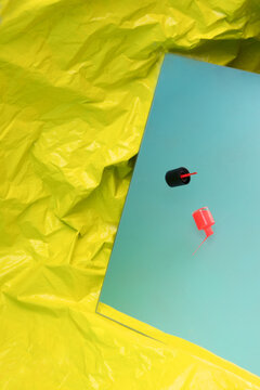 Orange nail polish lies on a blue mirror with yellow plastic