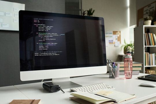 Computer monitor displaying programming script on an office desk