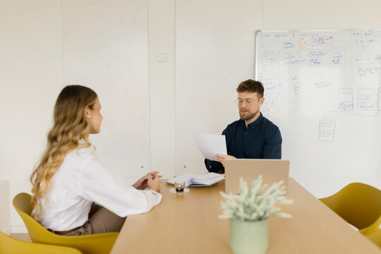 A male manager interviews a female candidate in a bright office