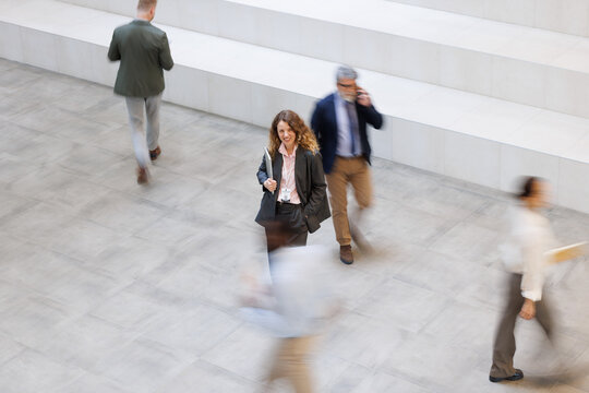 Confident businesswoman stands in a busy corporate office lobby