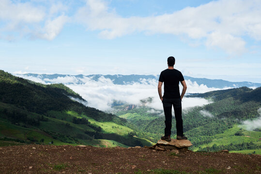 Thailand, Phu Chi Fa, traveler standing at the top of a hill with view over rice fields