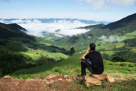 Thailand, Phu Chi Fa, traveler sitting at the top of a hill with view over rice fields