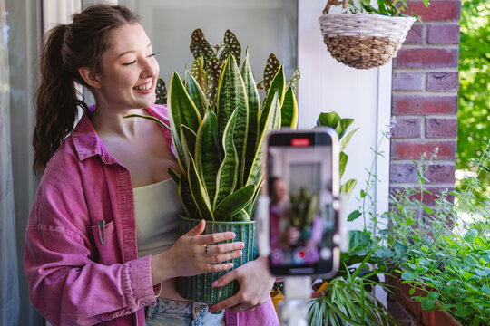 Woman records a gardening video with a smartphone on the balcony