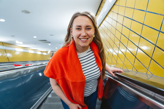 Smiling woman standing on escalator in a metro station during commute