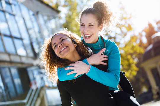 Happy young woman carrying friend piggyback