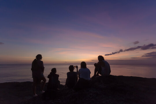 Indonesia, Bali, Lembongan island, friends at ocean coast at dusk