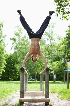 Germany, Bavaria, Young man doing handstand on railing