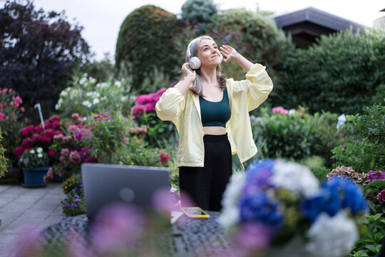 Woman listening to music with headphones in a lush garden