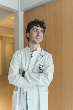 Smiling male doctor stands confidently in a bright hospital corridor