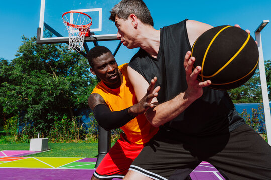Male basketball player dribbles the ball against a defender on court