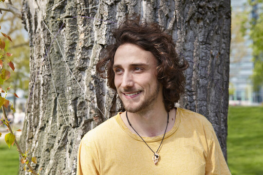 Smiling young man at tree trunk