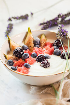 Bowl of Greek yoghurt with fig, watermelon, frozen berries and lavender honey