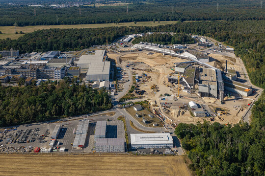 Aerial view of the Facility for Antiproton and Ion Research construction site with large industrial buildings, cranes, and earthworks surrounded by forest in Darmstadt, Hessen, Germany.