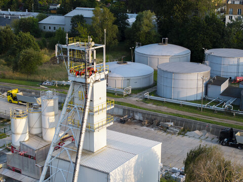 Aerial view of technical installations at the Wieliczka Salt Mine, featuring a tall metal headframe, large storage tanks, and industrial trucks in Wieliczka, Lesser Poland Voivode, Poland.