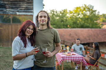 Obraz premium Happy young couple enjoying red wine at outdoor social gathering