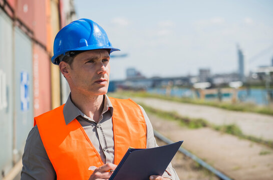 Portrait of man with blue safety helmet checking cargo containers
