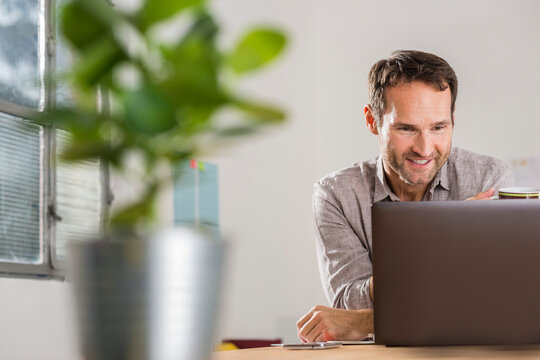 Smiling businessman looking at laptop in office