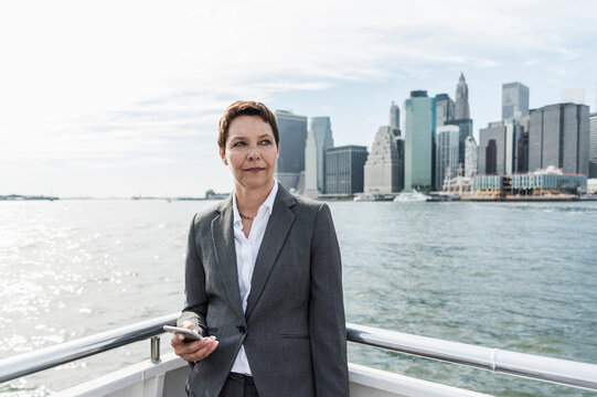 USA, Brooklyn, portrait of pensive businesswoman standing on boat