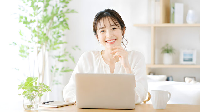 自宅のデスクでノートパソコンに向かいとびきりの笑顔を見せる女性