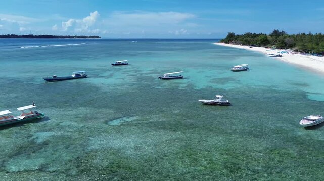 Aerial view of boats floating on pristine turquoise water near a white sandy beach in indonesia