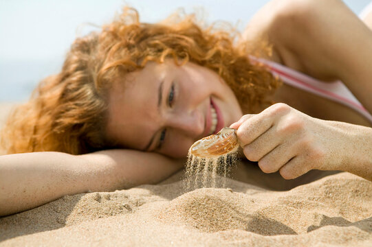 Young woman on beach, holding shell