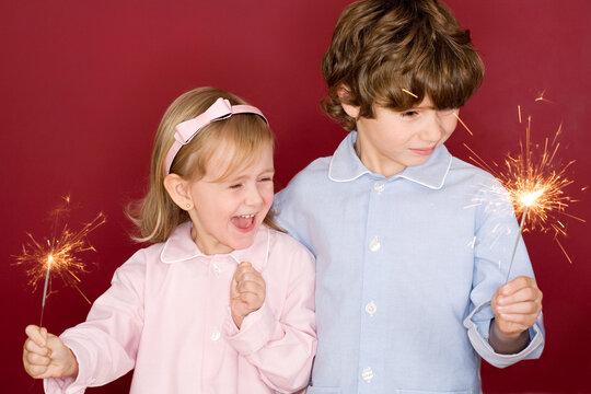 Boy (4-7) and girl (3-4) holding sparklers