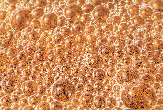 Golden sea foam bubbles cover the wet beach sand in Sagres