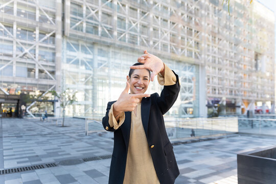 Smiling businesswoman makes a hand frame gesture outdoors in Quito