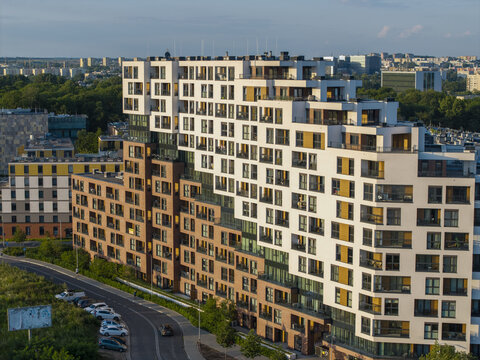 Aerial view of a modern residential apartment complex with a stepped architectural design featuring white and brick facades, situated in an urban area in Krakow, Lesser Poland Voivodeship, Poland.